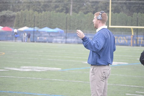 Hartman signaling the plays to his team members on the field from the sidelines.