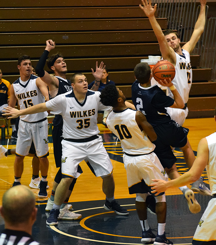 Mark Mullins (#12) blocking the shooters shot, defending the ball as well are Marcus Robinson (#10) and Mason Gross (#35). 