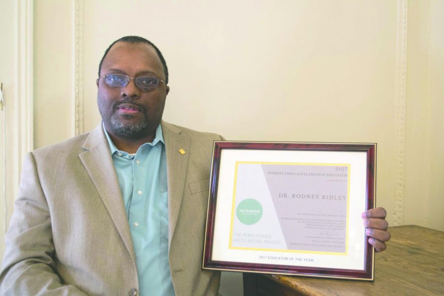 Dr. Rodney Ridley stands with his Pennsylvania Acceleration Educator of the Year award, given to him for his contributions to technology education. 