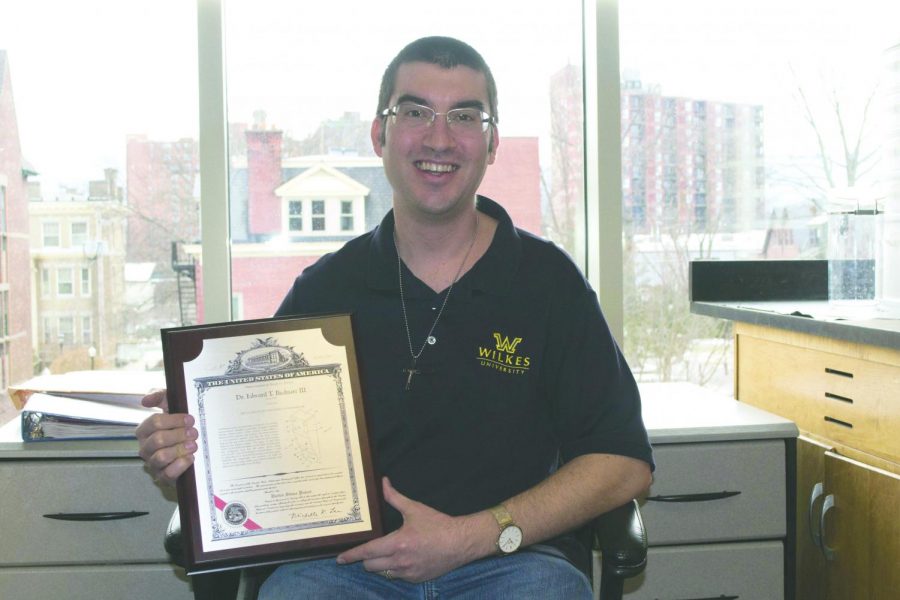 Dr. Edward T. Bednarz III sits with the certificate for his fourth patent. 