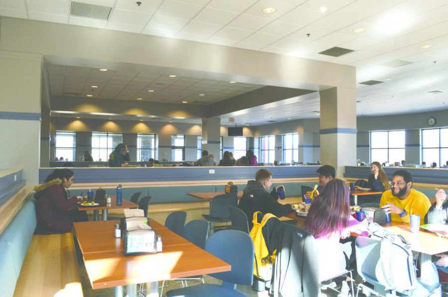 Joshua Shepard, a junior musical theater major, sits with friends in the newly rennovated cafeteria. In the image is the new wooden booth area, fitted with charging ports.