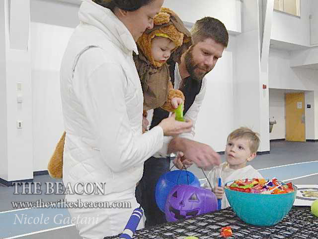 Wilkes footballs head coach Jonathan Drach and his family pick out candy from one of the tables.