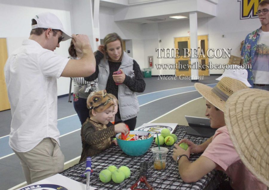 Families approach the table hosted by Wilkes Tennis while trick-or-treating at the SAAC event.