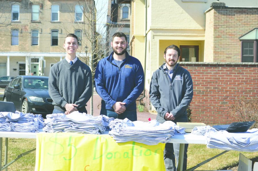 Student coordinators Cody Morcom, Dylan Fox, and Harrison Ferro stand with the table of t-shirts for participants. The walk accepted $5 donations for naloxone for the Wilkes-Barre Fire Department. 