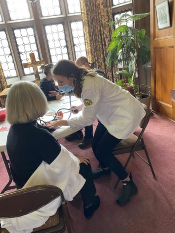 Kayla Aufiero checks blood pressure of attendee 