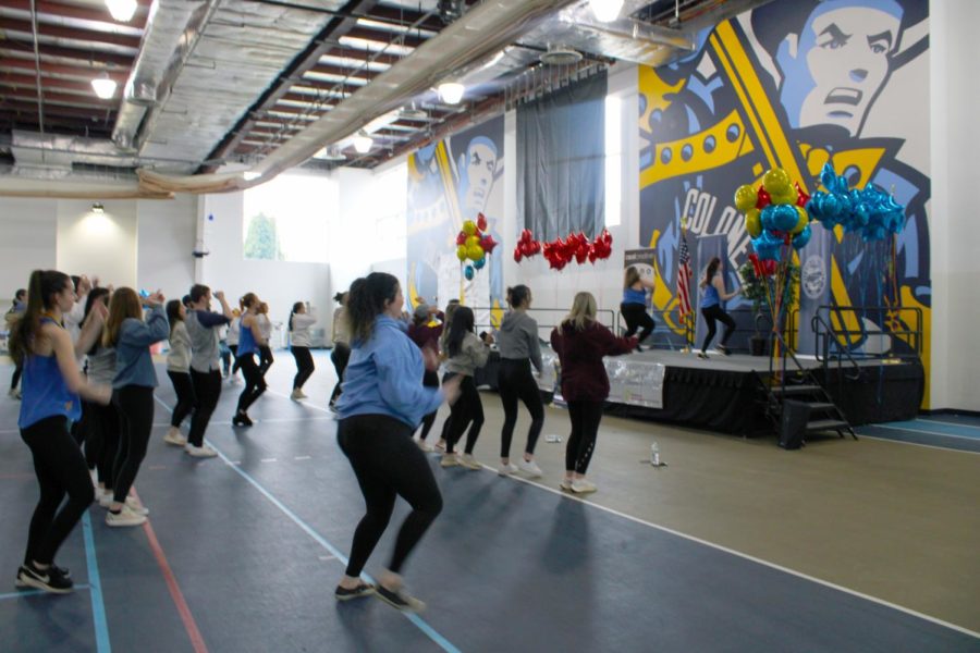 Courtney Corona (on stage, left) and Katie Ecker (on stage, right), captains of the dance team, teach attendees a dance lesson to keep the energy going throughout the dance-a-thon.