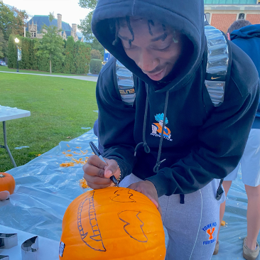Simms Janas, first-year mechanical engineering major, draws the face of a jack-o-lantern that will be cut later.