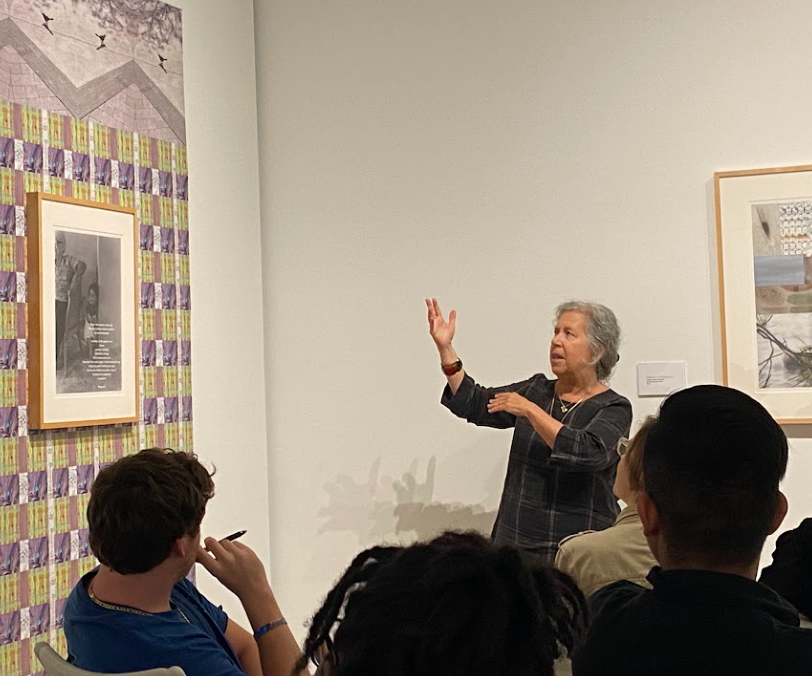 Vreeland lectures on her piece, Rhapsody which is comprised of a framed print and poem with a patterened print behind. Throughout her exhibit, she frequently examines the ways in which patterns are intersectional with memory, this piece being cognizant of that idea.