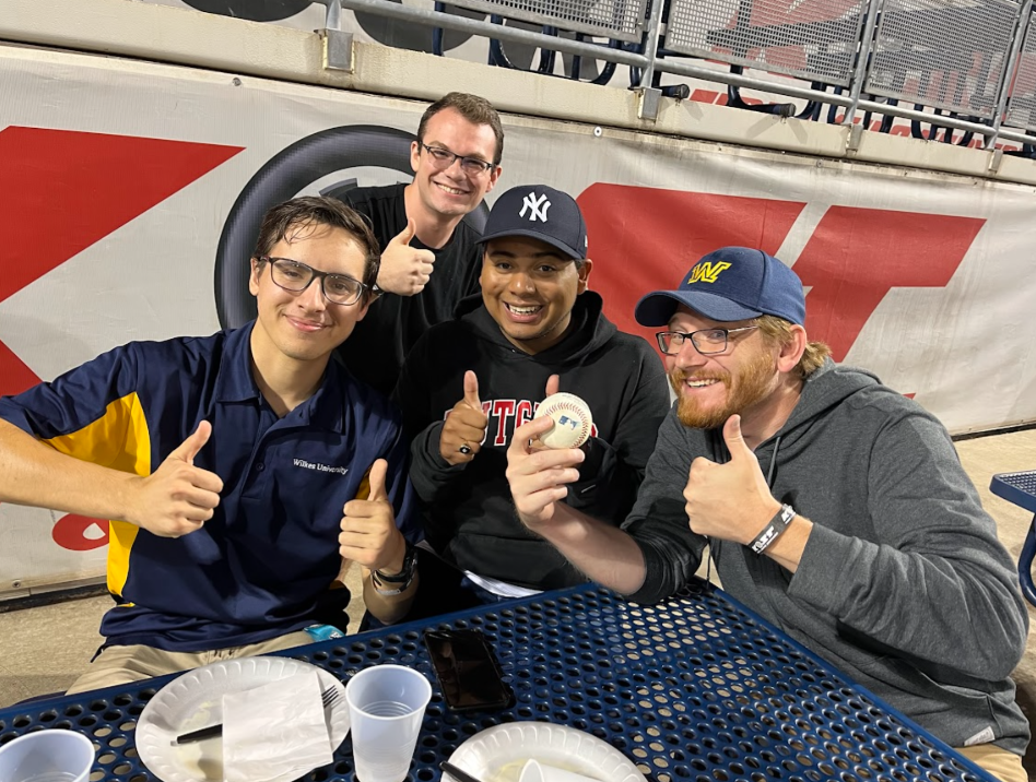 From left, Micheal Nowak, Anthony Antonette, Jordan Mosquera, and Dr. Jonathan Kuiken celebrate an amazing catch in the audience at a Railriders game. Honors students attended the game during the fall 2022 semester.